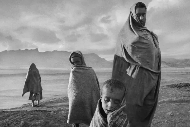 SEBSTIÃO SALGADO Draped in blankets to keep out the cold morning wind, refugees wait outside Korem camp, Ethiopia 1984 Silver gelatin print 40 x 50 cm (16 x 20 in.)
