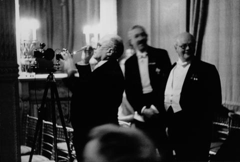 Dr. Erich Salomon überprüft mit einer Taschenlampe die Einstellungen seiner Leica Kameras. Botschaft von Österreich, London 1937. Foto von Peter Hunter